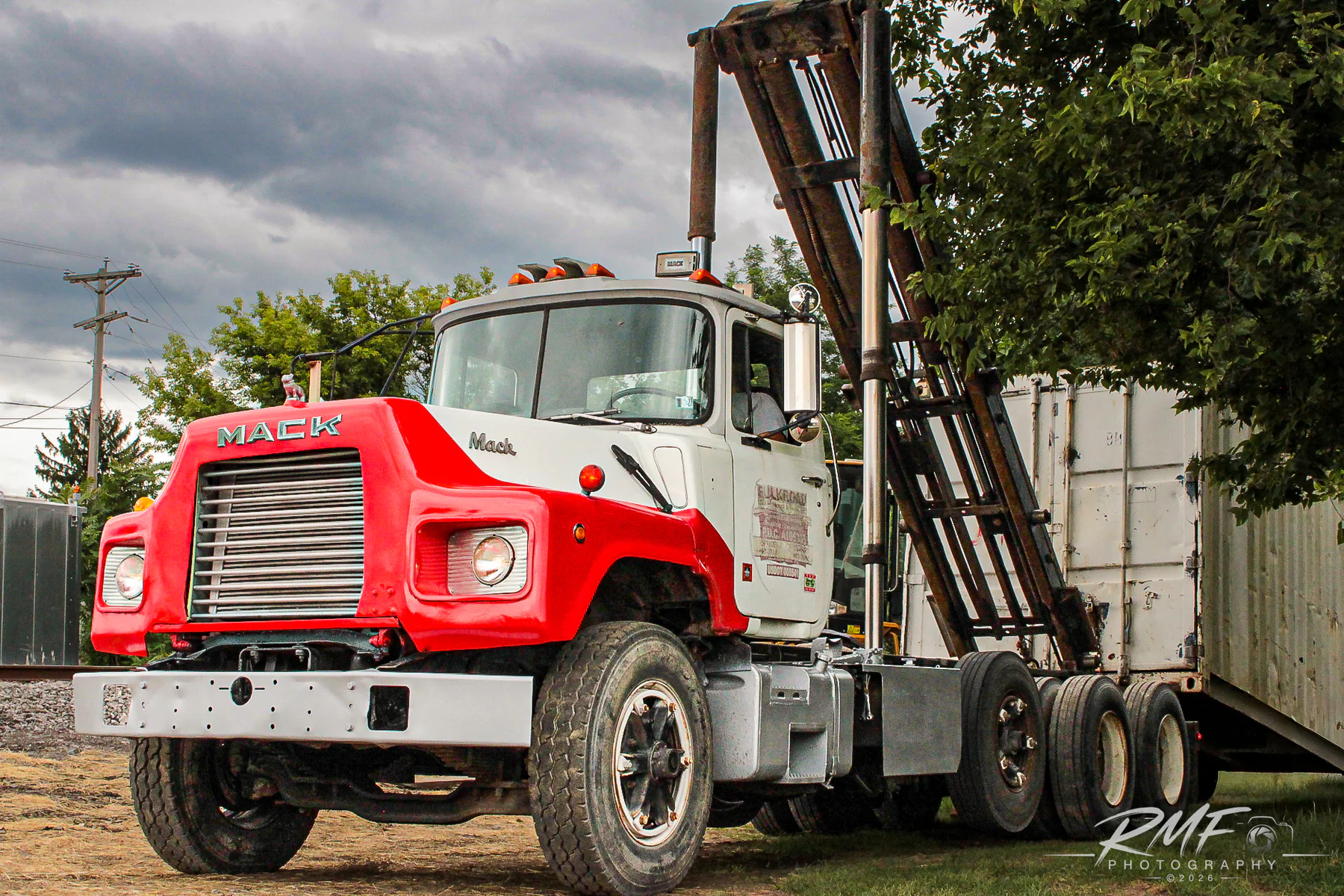 Classic red and white Mack truck photographed beneath a dramatic Pennsylvania sky
