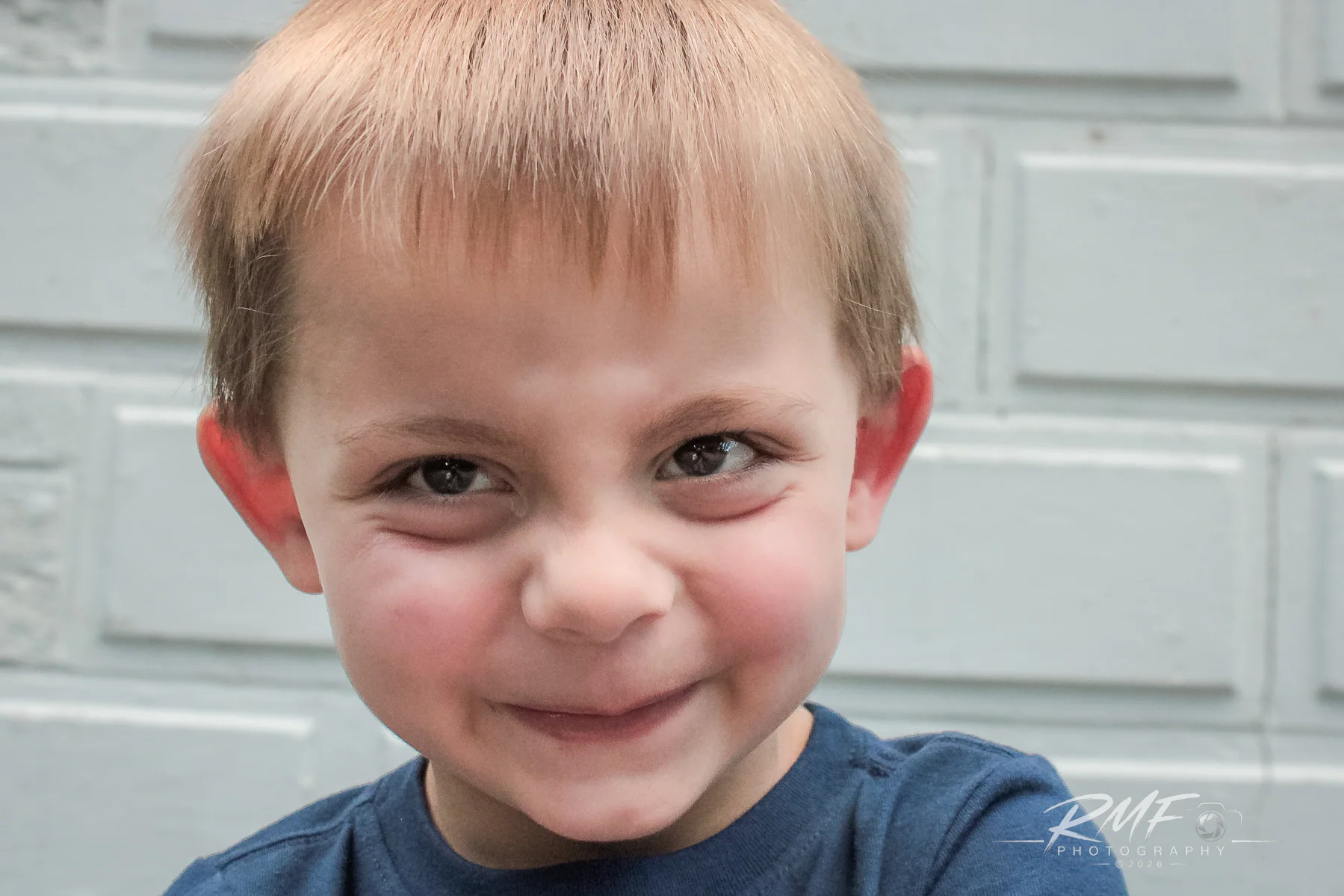 Natural-light portrait of a smiling young boy photographed by RMF Photography