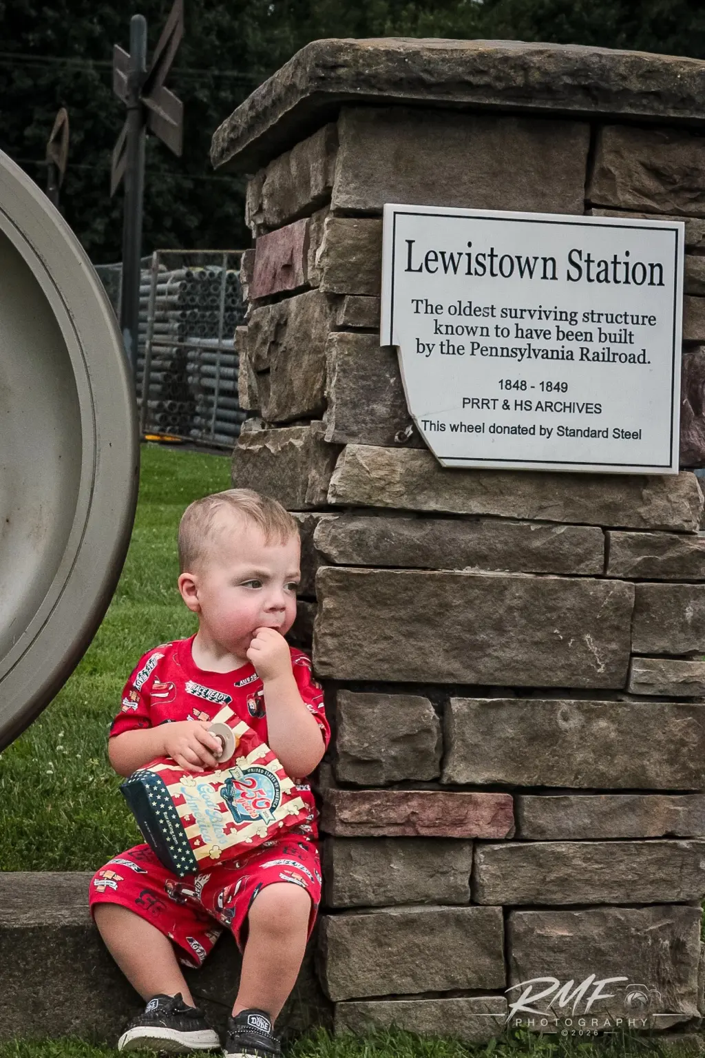 Young child seated beside the historic Lewistown Station marker