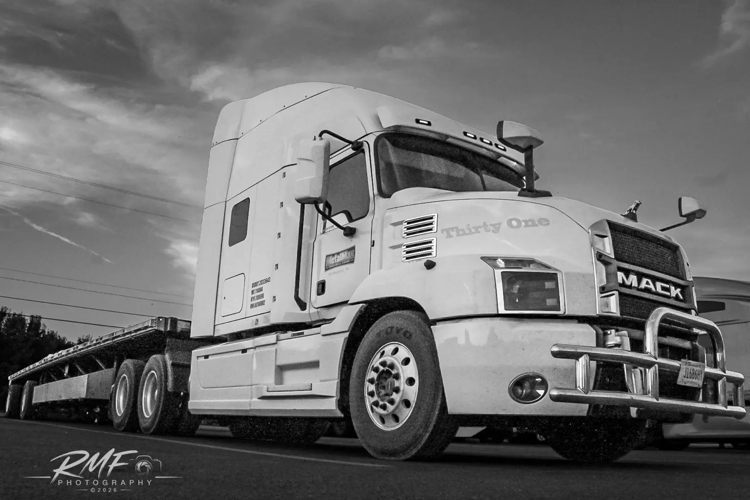 Black-and-white low-angle portrait of a Mack tractor and flatbed