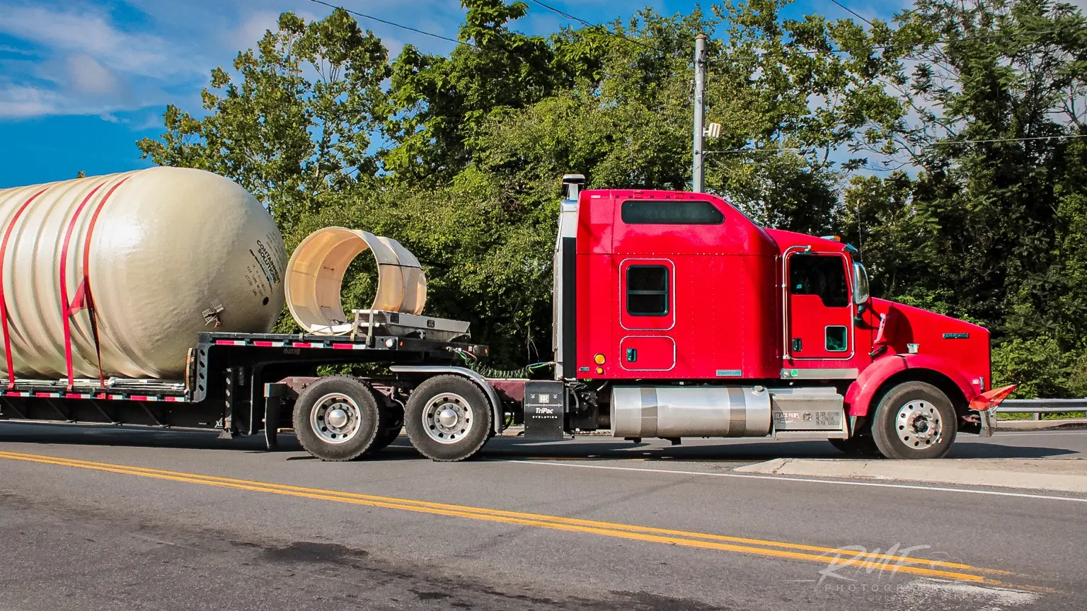 Red tractor hauling an oversized tank