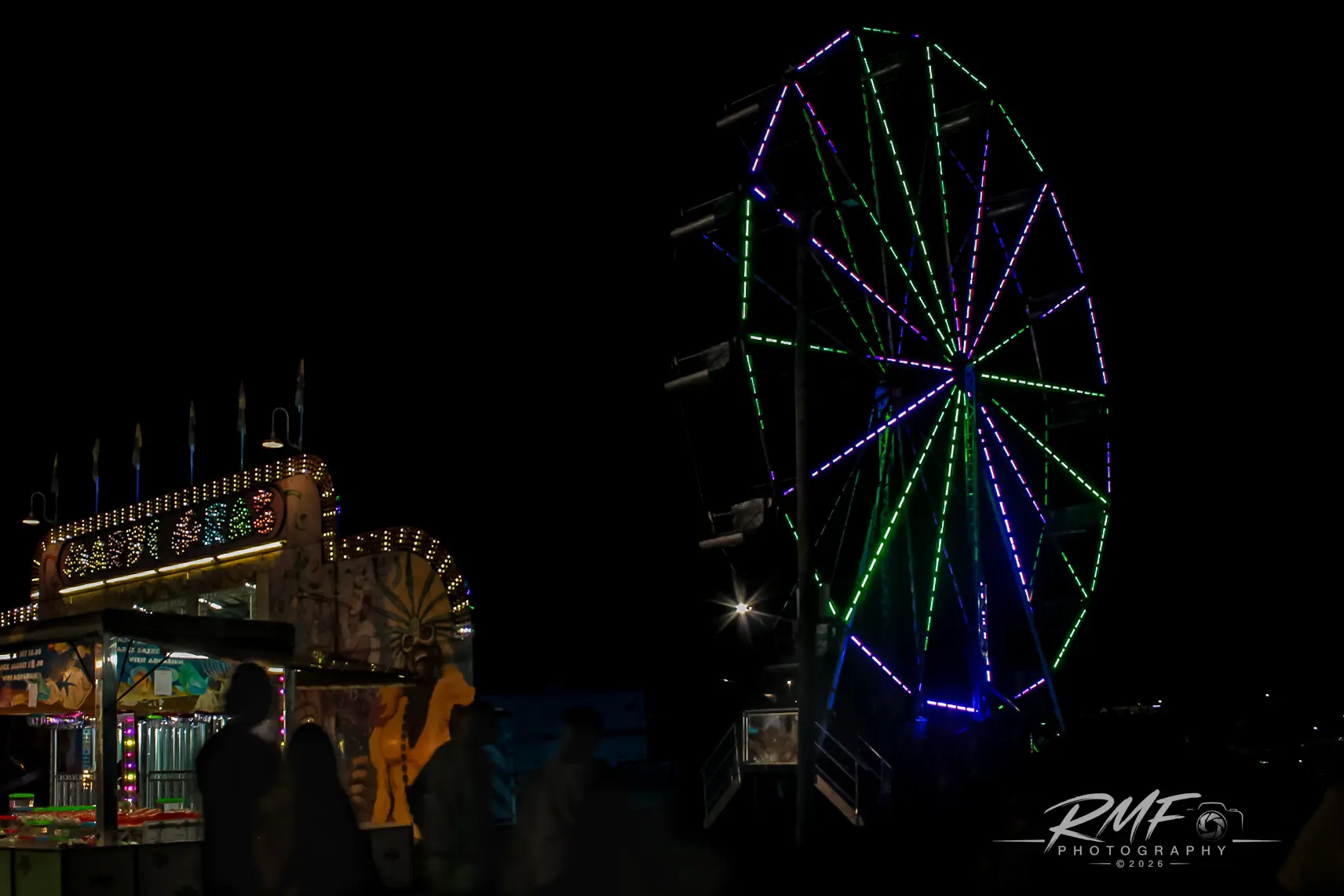 Ferris wheel and midway lights at a nighttime fair