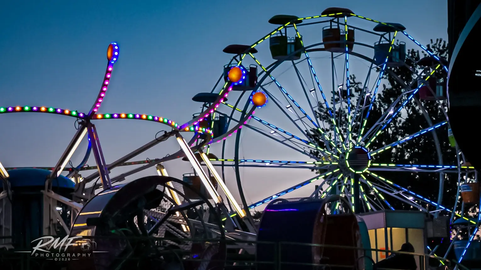 Ferris wheel and amusement ride lights at dusk