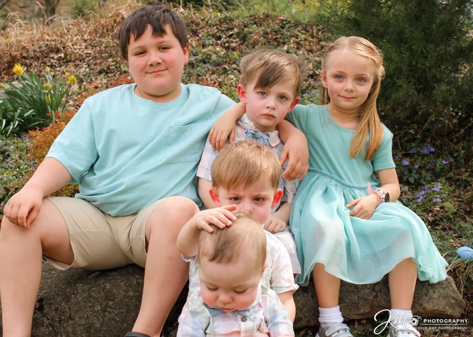 Five siblings gathered for a relaxed outdoor family portrait