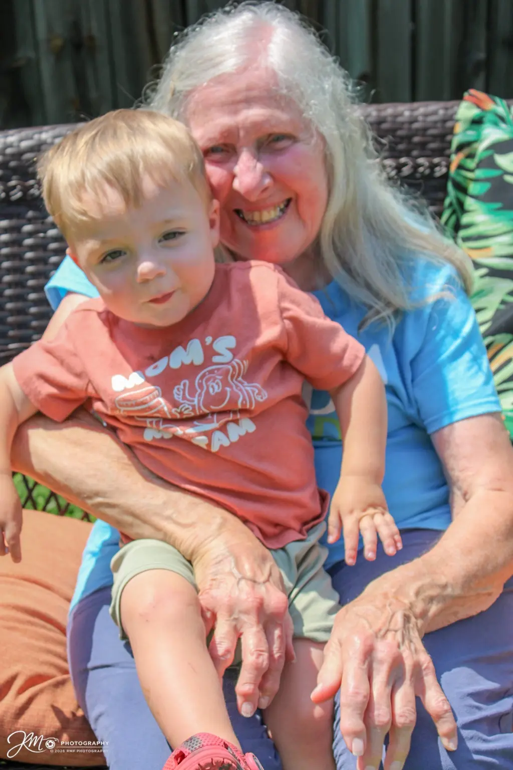 Grandmother smiling while holding her young grandson outdoors