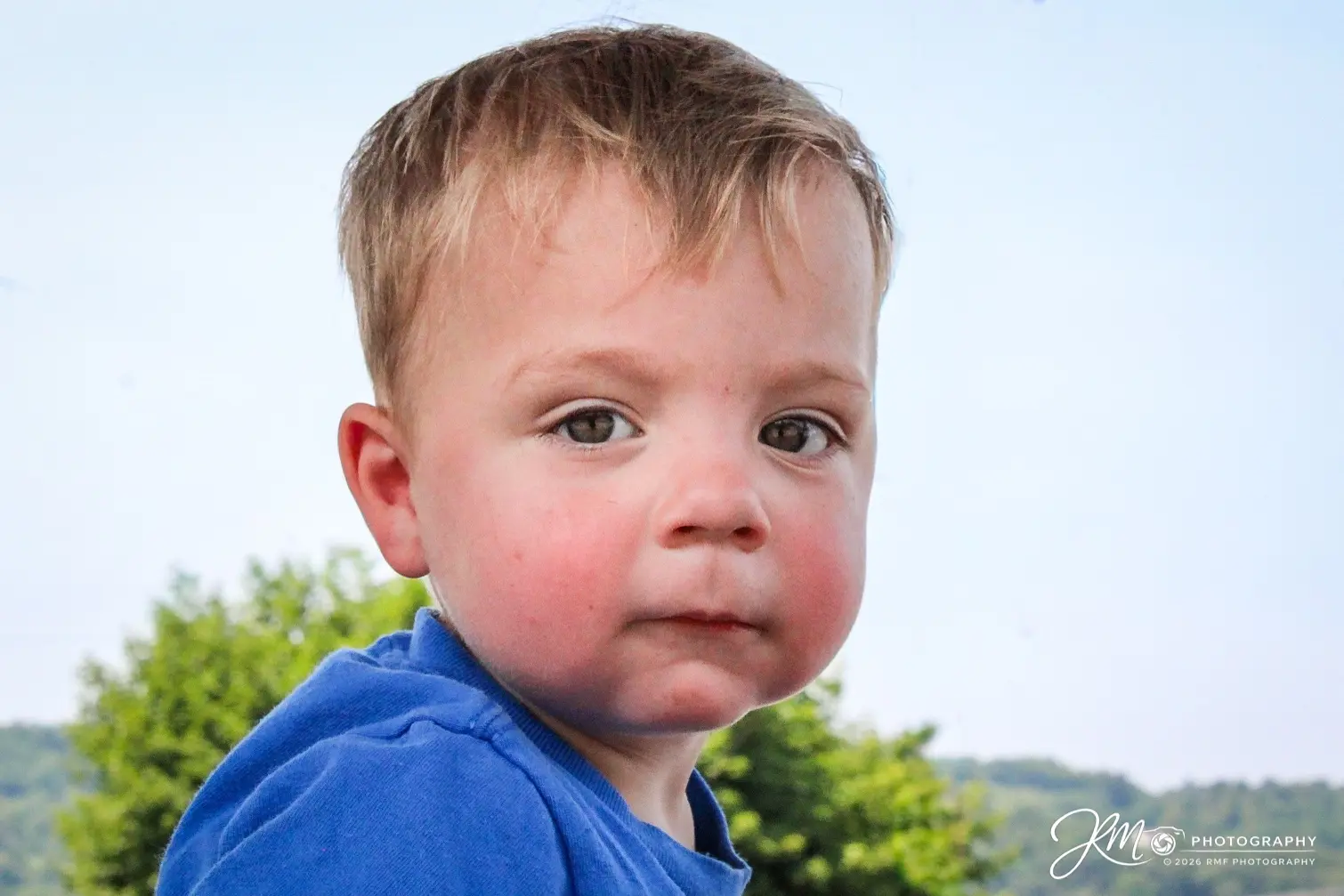 Close outdoor portrait of a young boy in a blue shirt