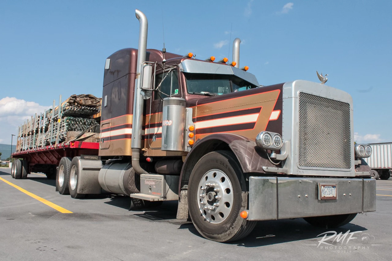 Maroon classic long-nose tractor and loaded flatbed photographed in color