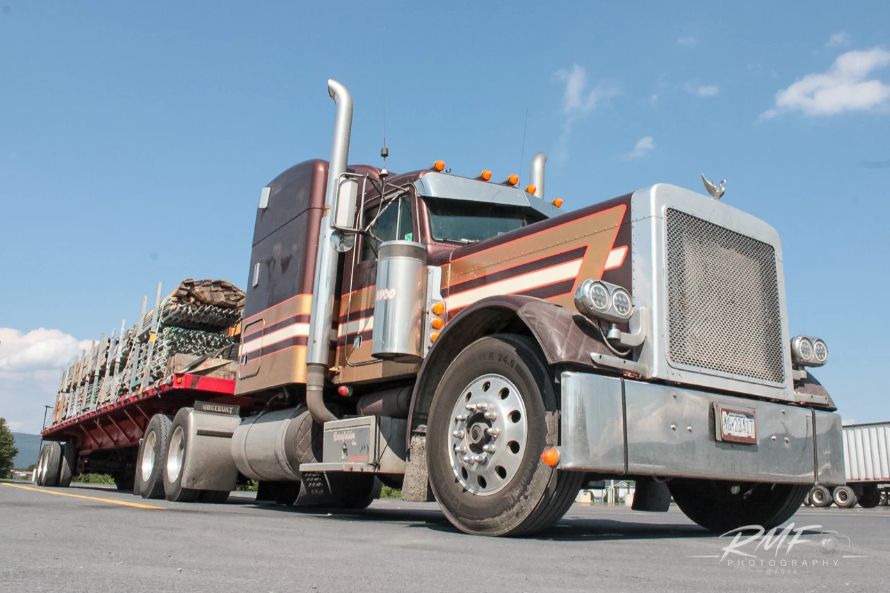 Low-angle color portrait of a maroon classic tractor and loaded flatbed